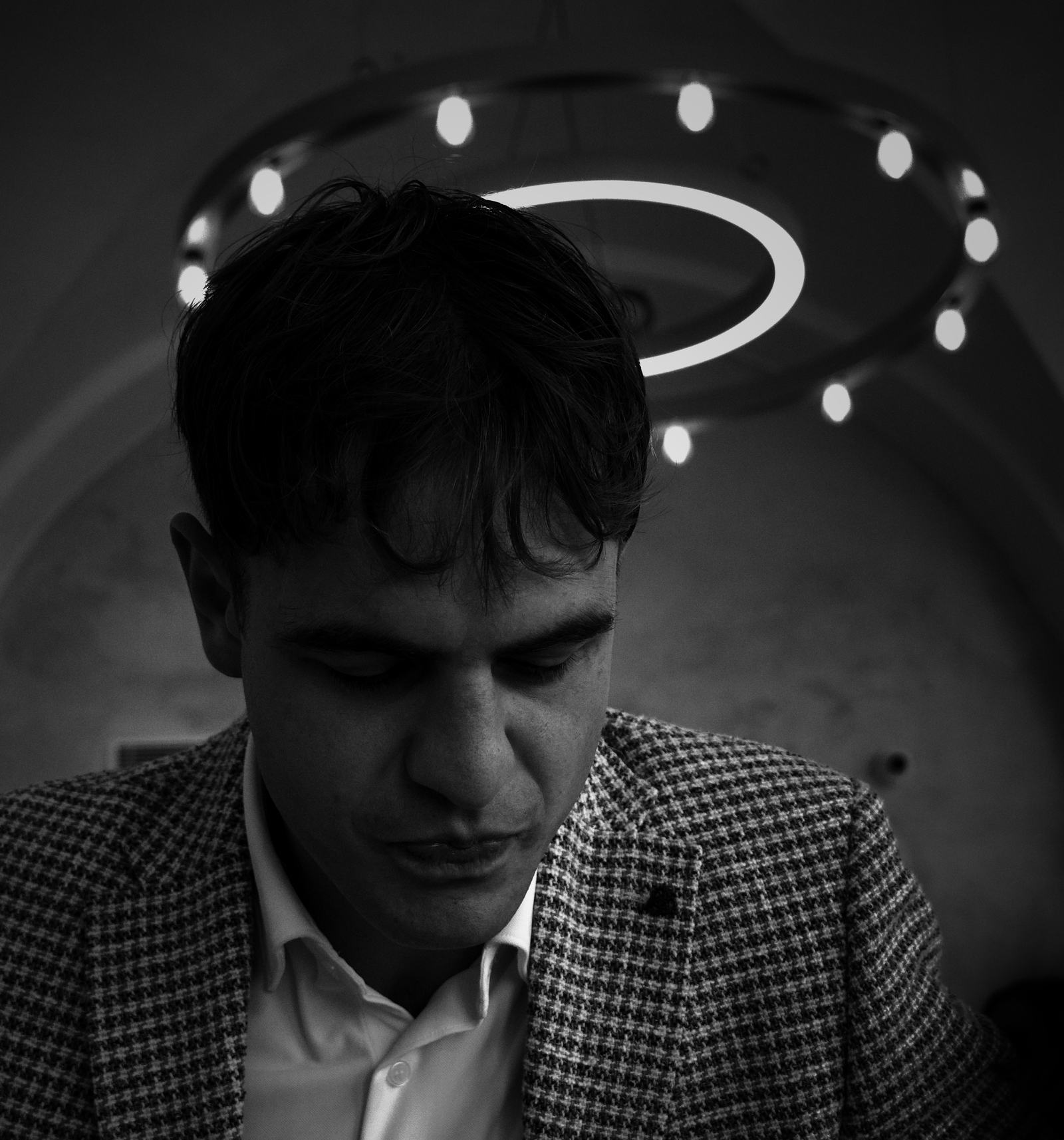 Ivas at a table, reading, under a ring of lights